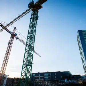 Bouwkranen en hoogbouw in een stedelijk ontwikkelingsgebied waar meerdere ruimtelijke opgaven samenkomen in de openbare ruimte.